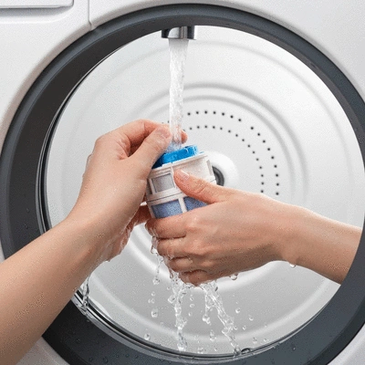 Person cleaning a washing machine's pump filter, close-up with debris